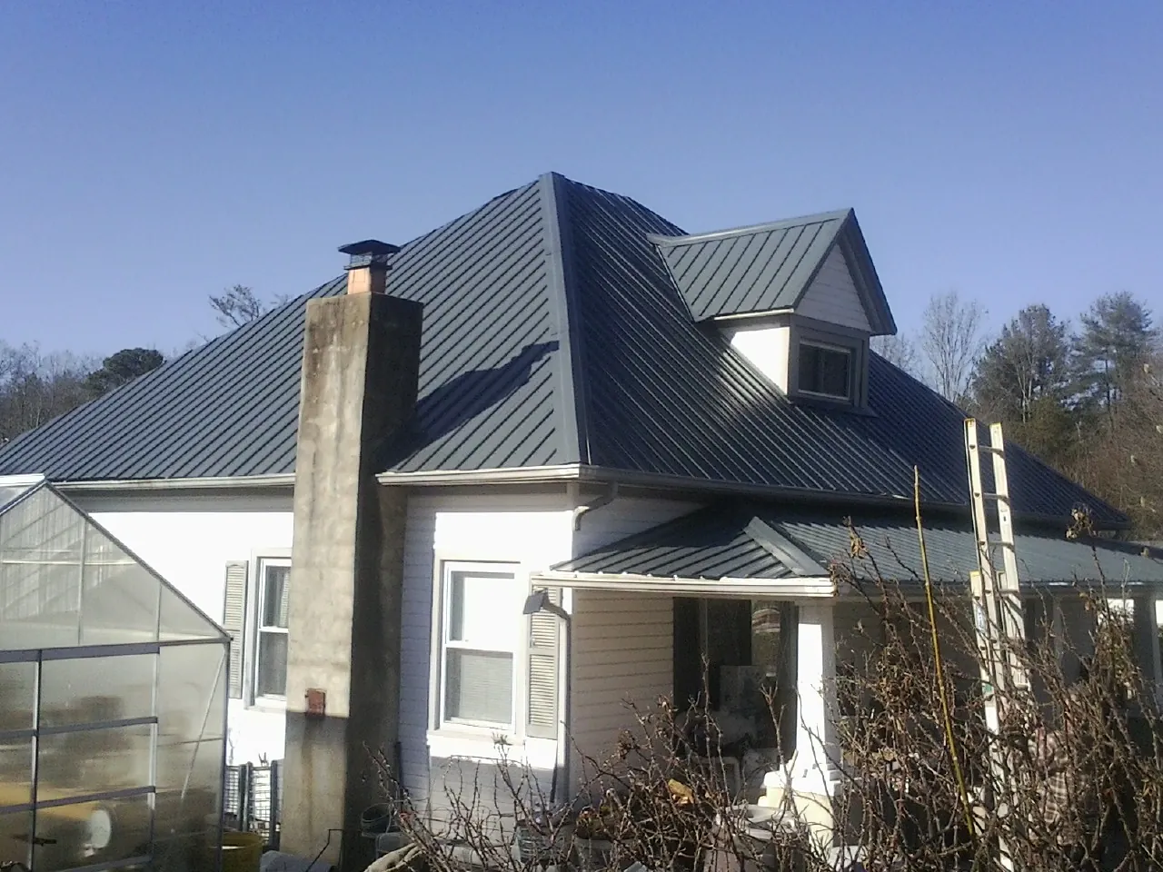 Dark blue standing seam metal roof on a white farmhouse with dormer — Slate & Tile Roof Repair by Roofing Brothers in Arco