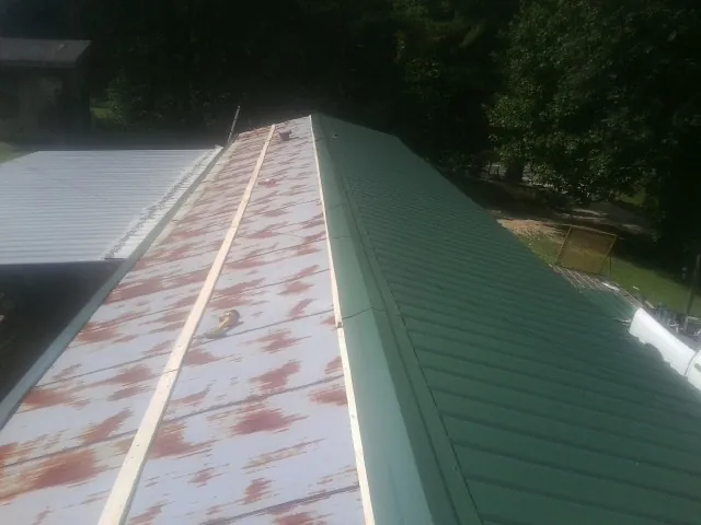 Old rusted panels beside newly installed green metal roofing — Wind Damage Roof Repair by Roofing Brothers in Arco