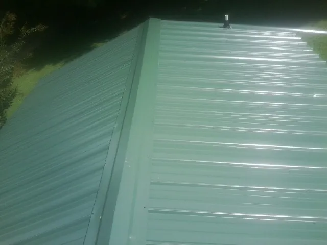 New green metal panels meeting at the ridge of a roof — Flat Roof Repair work by our crew in Arco
