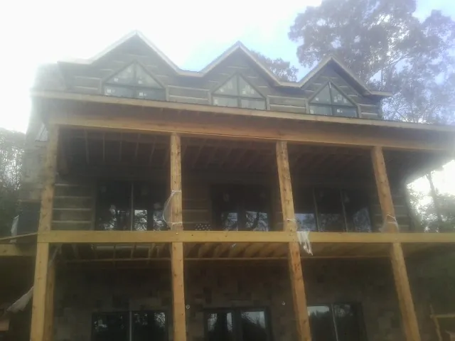 Dormers and porch framing on a large log home under construction — Roof Coating work by our crew in Arco