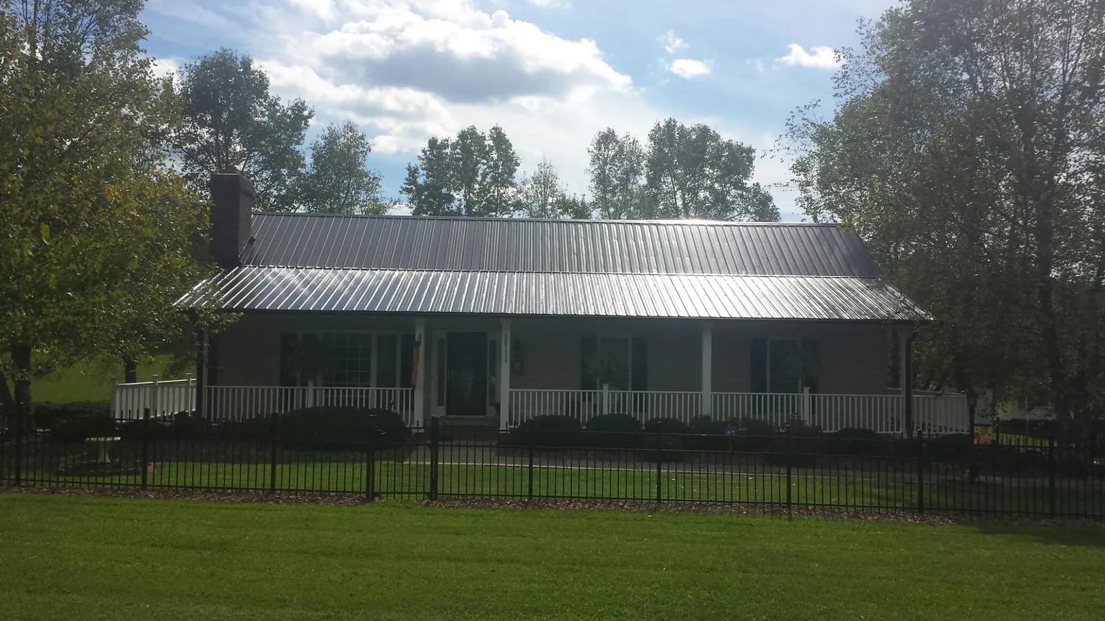 Gray metal roof on a brick ranch with a full width front porch — Gutter Guard Installation work by our crew in Arco