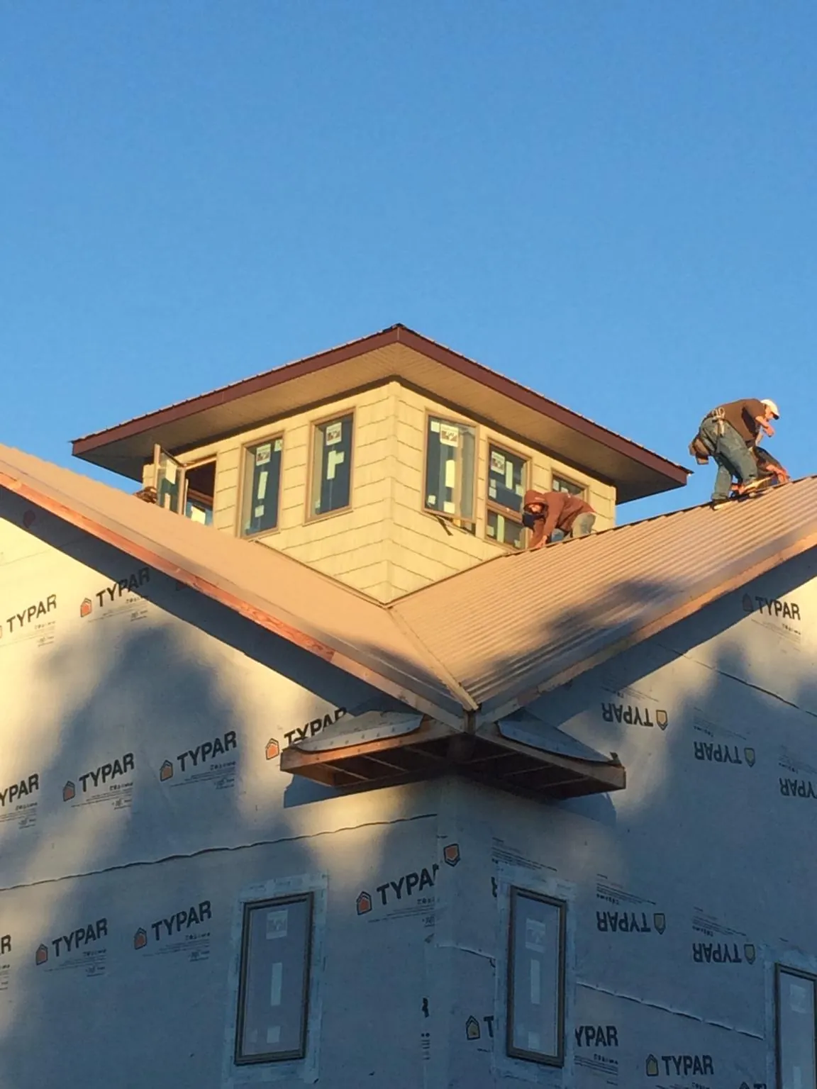 Roofers working around a rooftop cupola on a new metal roof at sunset — Roof Waterproofing in Arco by Roofing Brothers